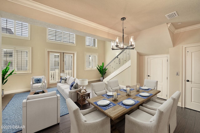 dining room with dark wood-type flooring, a textured ceiling, crown molding, and a towering ceiling