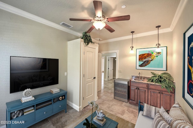 tiled living room featuring ceiling fan, a textured ceiling, sink, and ornamental molding