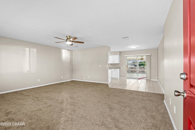 unfurnished room featuring light carpet, baseboards, a ceiling fan, a textured ceiling, and light tile patterned flooring