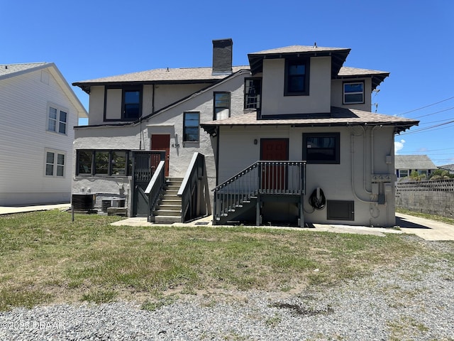 rear view of property with cooling unit and a yard