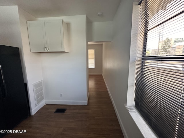 kitchen featuring white cabinets, black fridge, and dark hardwood / wood-style flooring