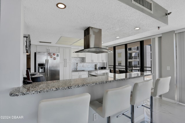 kitchen with kitchen peninsula, island exhaust hood, white cabinets, and stainless steel appliances