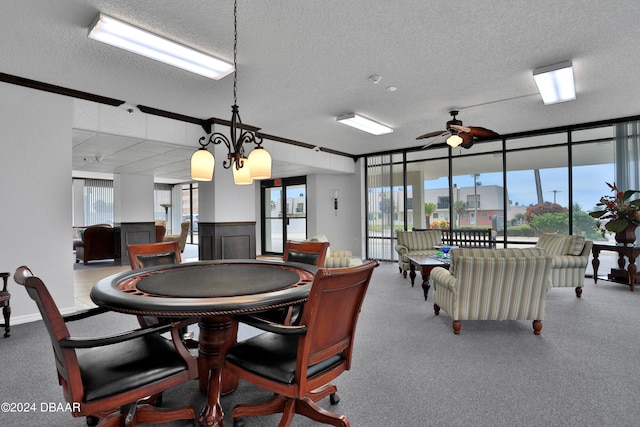 playroom with expansive windows, a textured ceiling, a healthy amount of sunlight, and ceiling fan with notable chandelier