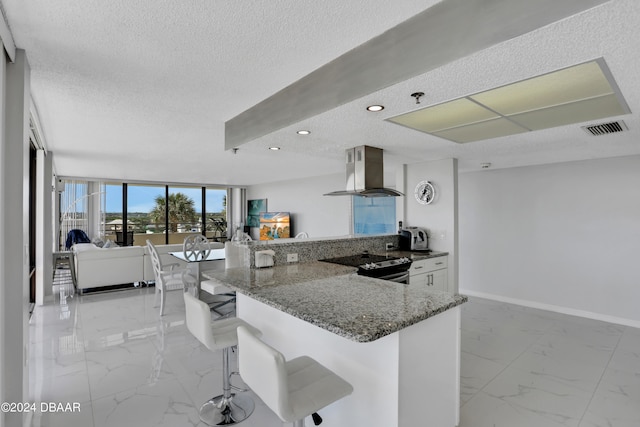 kitchen with stainless steel range with electric cooktop, range hood, a textured ceiling, a kitchen breakfast bar, and kitchen peninsula