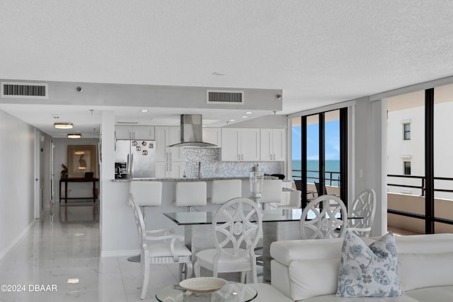 dining area with sink, a water view, floor to ceiling windows, and a textured ceiling