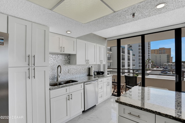 kitchen with dishwasher, white cabinets, sink, tasteful backsplash, and stone counters