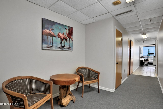 hallway featuring light colored carpet and a paneled ceiling