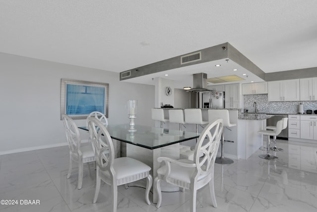 dining space featuring sink and a textured ceiling