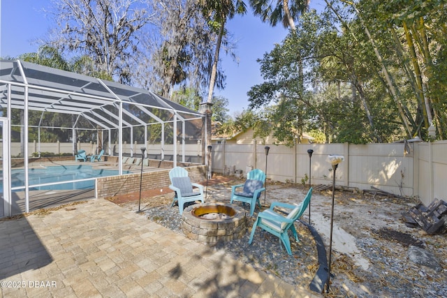 view of patio featuring glass enclosure, a fire pit, a fenced in pool, and a fenced backyard