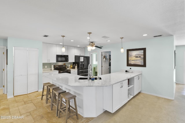 kitchen featuring visible vents, black appliances, a peninsula, white cabinetry, and a sink