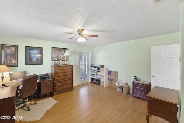 office space featuring a textured ceiling, light wood-type flooring, and ceiling fan