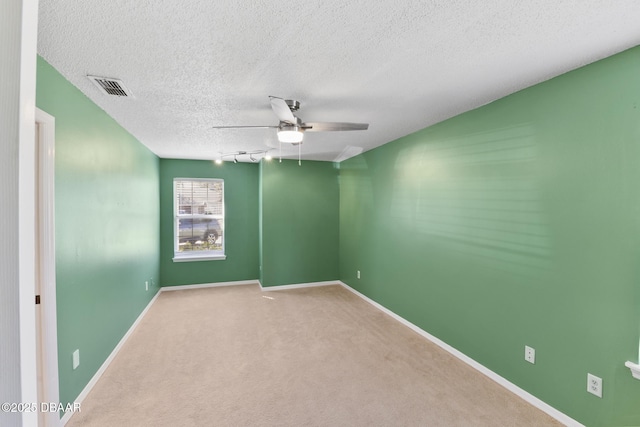 empty room with baseboards, visible vents, ceiling fan, a textured ceiling, and carpet flooring