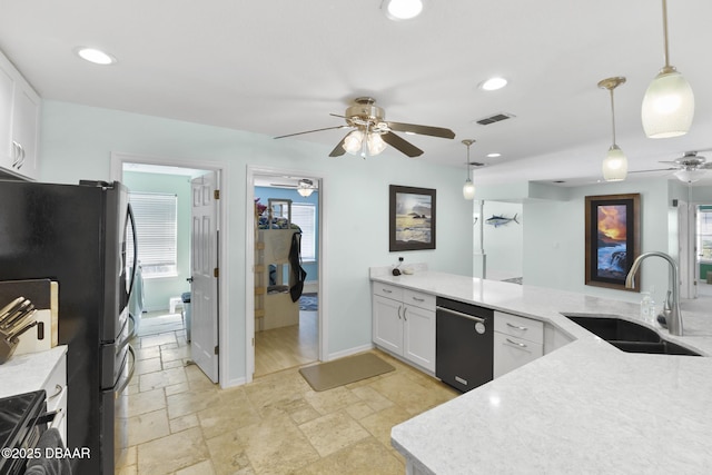 kitchen with stone tile floors, visible vents, freestanding refrigerator, a sink, and dishwasher