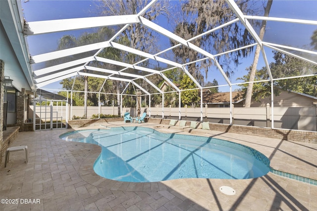 view of swimming pool featuring glass enclosure, a patio, a fenced backyard, and a fenced in pool