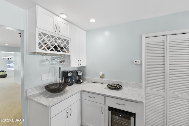 kitchen with wine cooler, recessed lighting, white cabinetry, and light stone counters