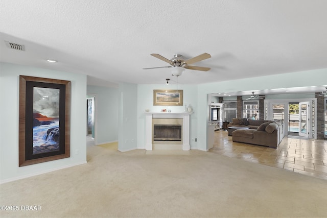 unfurnished living room featuring carpet flooring, visible vents, a textured ceiling, and a fireplace with flush hearth