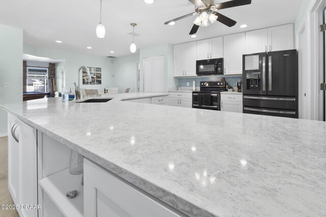 kitchen with tasteful backsplash, black appliances, light stone countertops, white cabinetry, and a sink