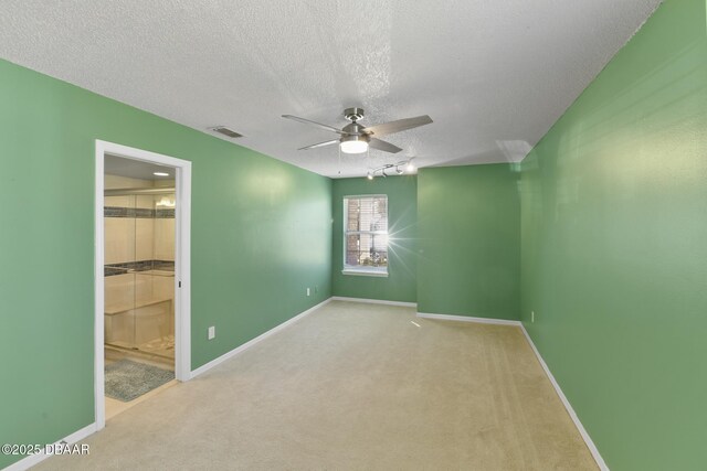 spare room with visible vents, baseboards, carpet, and a textured ceiling