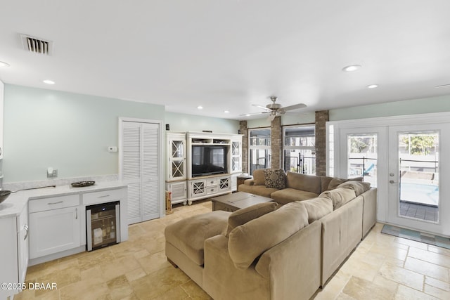 living room featuring beverage cooler, visible vents, a wealth of natural light, and stone tile flooring