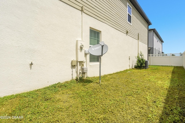 view of side of property featuring a lawn, fence, and stucco siding