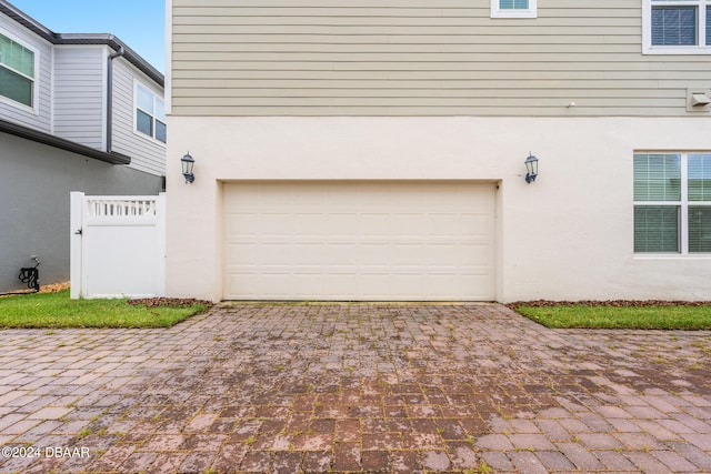 garage featuring decorative driveway and fence