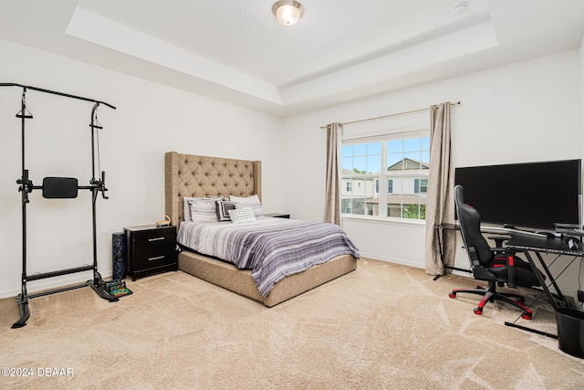 carpeted bedroom featuring baseboards and a raised ceiling