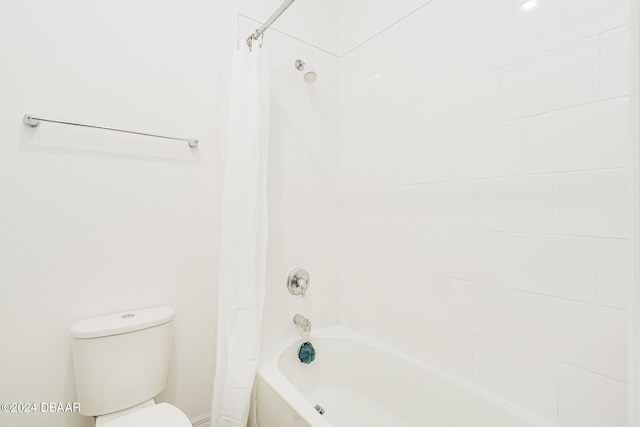bathroom featuring toilet and shower / bath combination with curtain