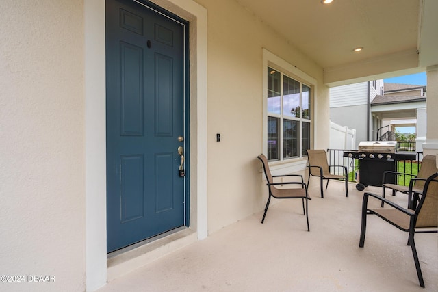 view of exterior entry with stucco siding and a porch