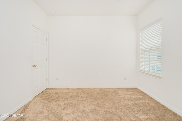 spare room with baseboards, light colored carpet, and a healthy amount of sunlight