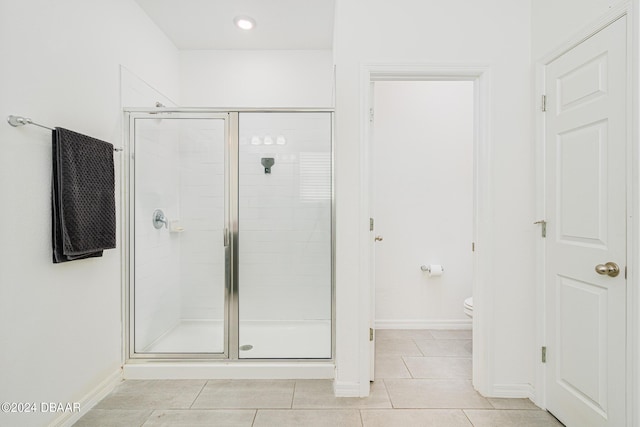 bathroom featuring baseboards, tile patterned flooring, a shower stall, and toilet