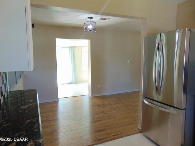 kitchen with light wood-type flooring, baseboards, freestanding refrigerator, and visible vents