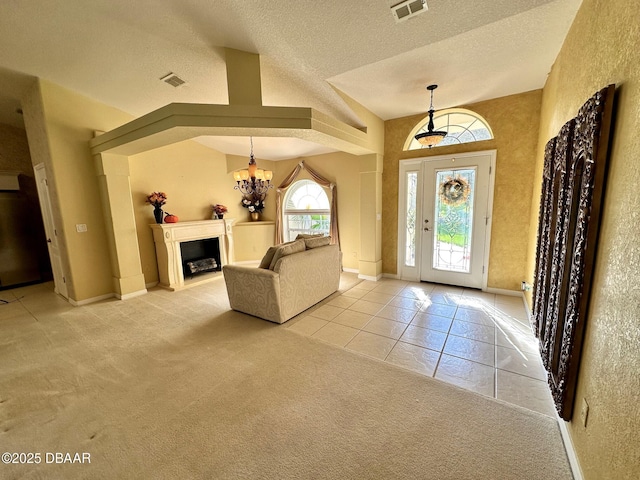 entrance foyer featuring a notable chandelier, light tile patterned floors, a textured ceiling, and lofted ceiling