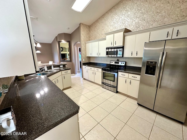 kitchen with kitchen peninsula, sink, light tile patterned floors, and stainless steel appliances