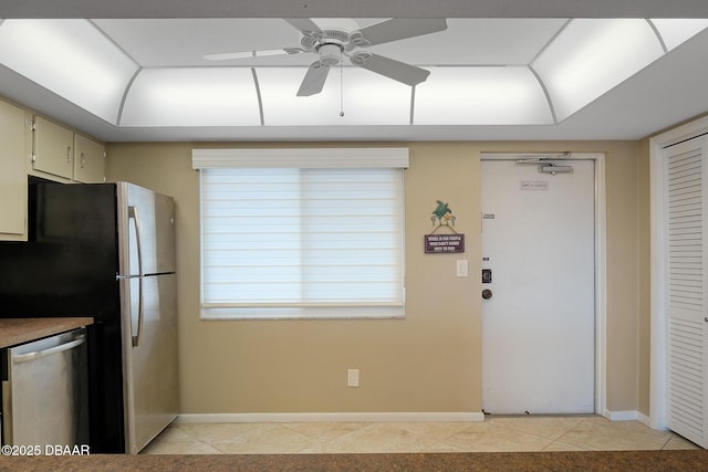 kitchen with a tray ceiling, stainless steel appliances, ceiling fan, and light tile patterned floors