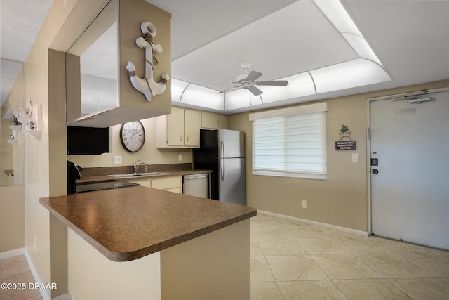 kitchen with kitchen peninsula, a tray ceiling, sink, ceiling fan, and appliances with stainless steel finishes