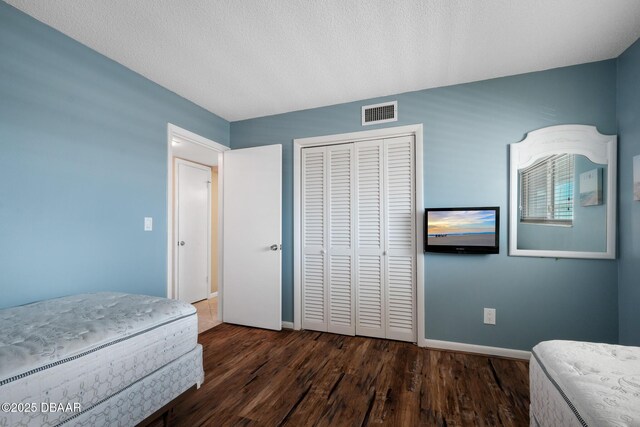 bedroom featuring dark wood-type flooring, a textured ceiling, and a closet