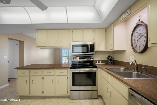 kitchen featuring light tile patterned flooring, appliances with stainless steel finishes, sink, and cream cabinets