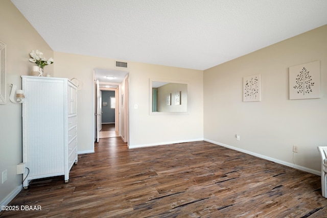 unfurnished room featuring a textured ceiling and dark wood-type flooring