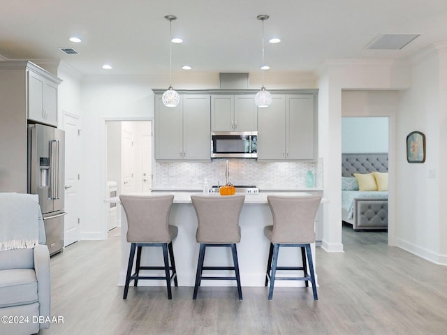 kitchen featuring stainless steel appliances, an island with sink, hanging light fixtures, and gray cabinetry