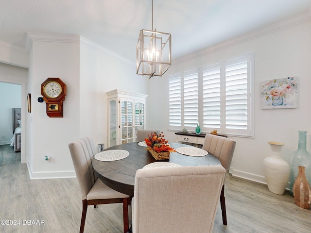 dining area with light wood-type flooring, a notable chandelier, and crown molding