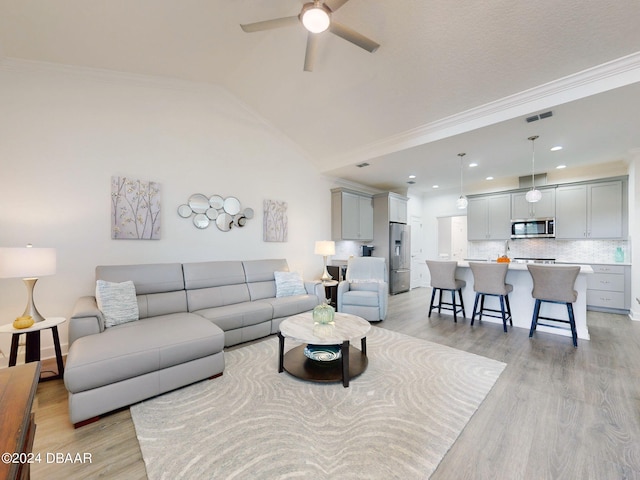 living room with crown molding, vaulted ceiling, ceiling fan, and light wood-type flooring