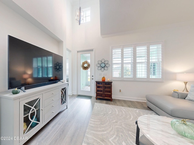 living room featuring a high ceiling, a notable chandelier, and light hardwood / wood-style flooring