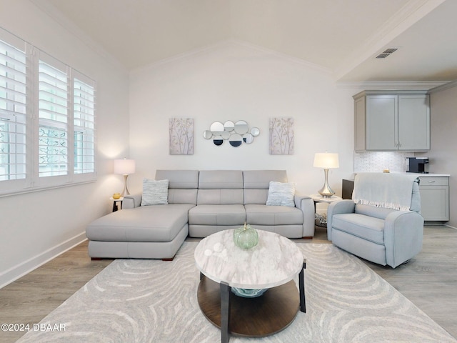 living room with light hardwood / wood-style flooring, ornamental molding, and vaulted ceiling