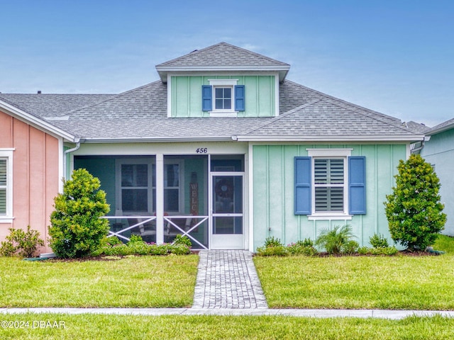 view of front of home with a front yard and a sunroom