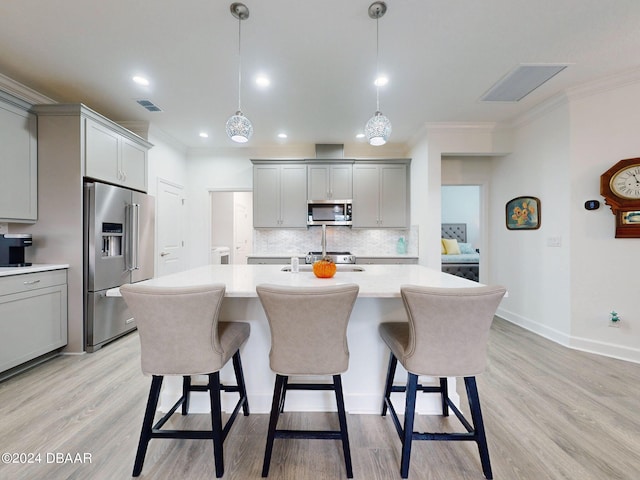 kitchen with gray cabinetry, ornamental molding, stainless steel appliances, light wood-type flooring, and decorative light fixtures