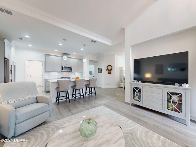 living room with ornamental molding and light wood-type flooring