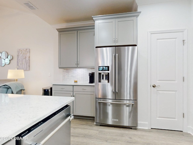 kitchen with tasteful backsplash, light wood-type flooring, gray cabinetry, and appliances with stainless steel finishes