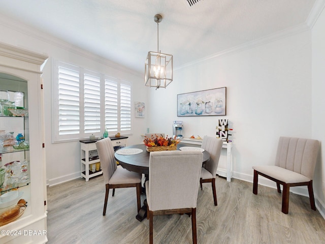 dining space with light hardwood / wood-style flooring, a notable chandelier, and crown molding