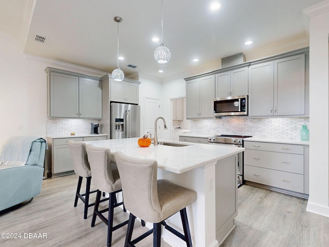 kitchen with sink, gray cabinetry, a center island with sink, appliances with stainless steel finishes, and pendant lighting