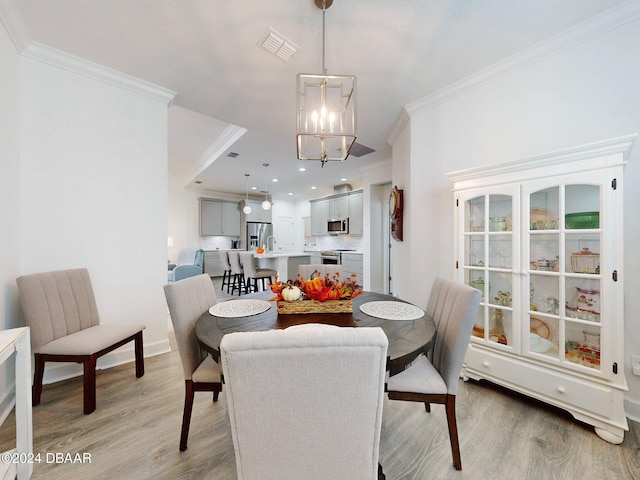 dining space featuring an inviting chandelier, ornamental molding, and light hardwood / wood-style floors